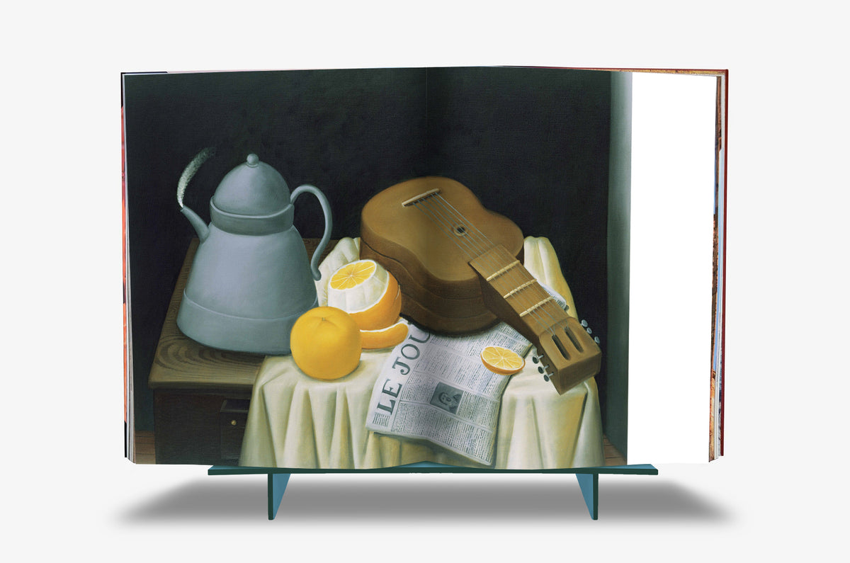 Fernando Botero XXL by Assouline: Full-spread reproduction of Botero's still life —a classical guitar, a pewter teapot, whole and halved oranges, and a folded French newspaper on a white-draped table against a dark background.