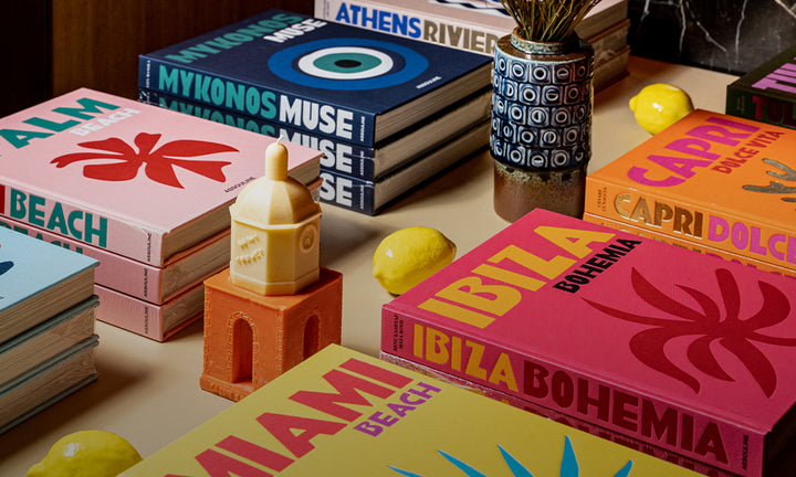 Collection of colorful books laying on a beige table with decorative accents and yellow lemons